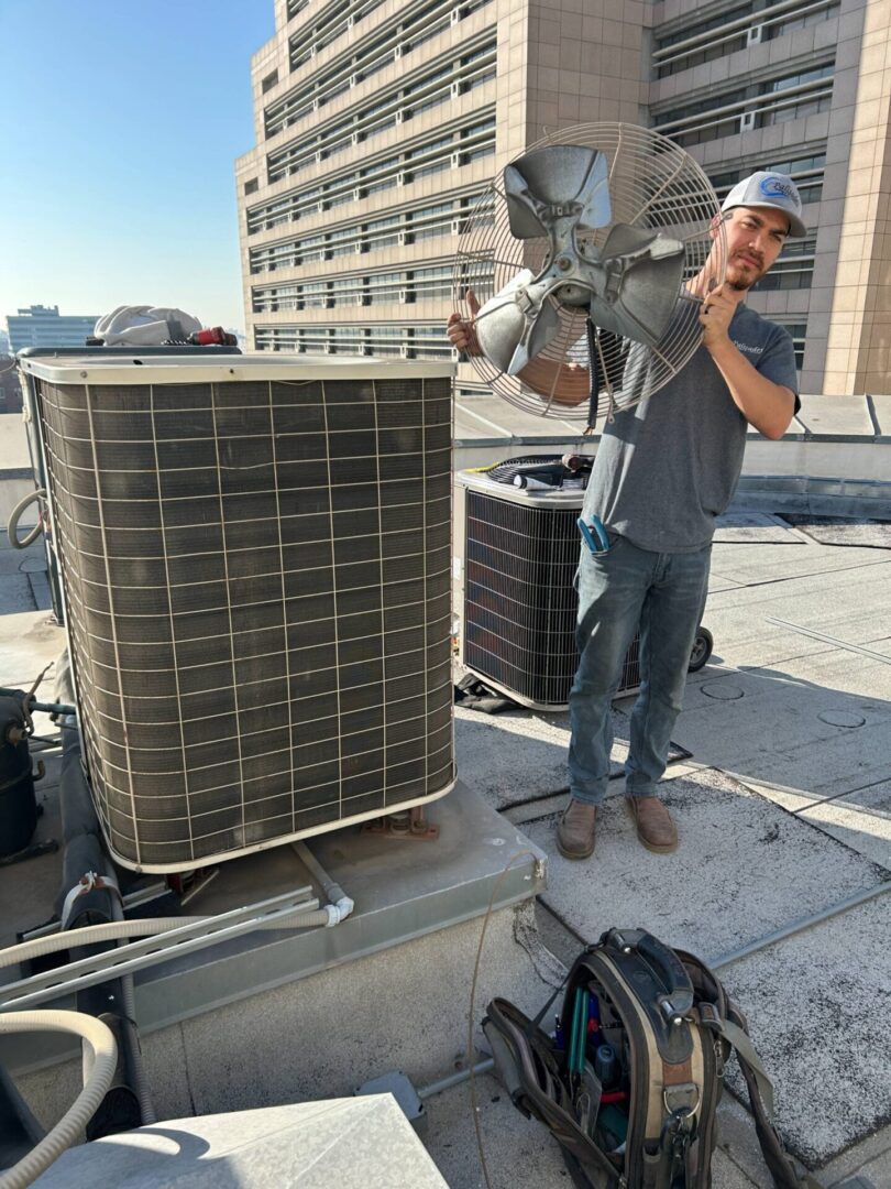 Man holding fan near HVAC system