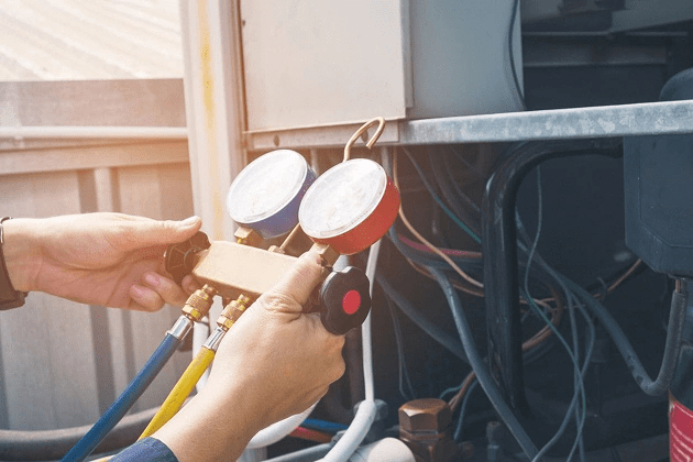 Hands adjusting HVAC pressure gauges